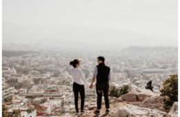 Happy Couple Holding Hands on Mountain Overlooking View